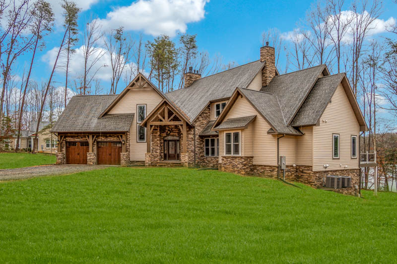 A large rustic timber-and-stone custom estate home with a timber-framed entry portico and a wide lawn