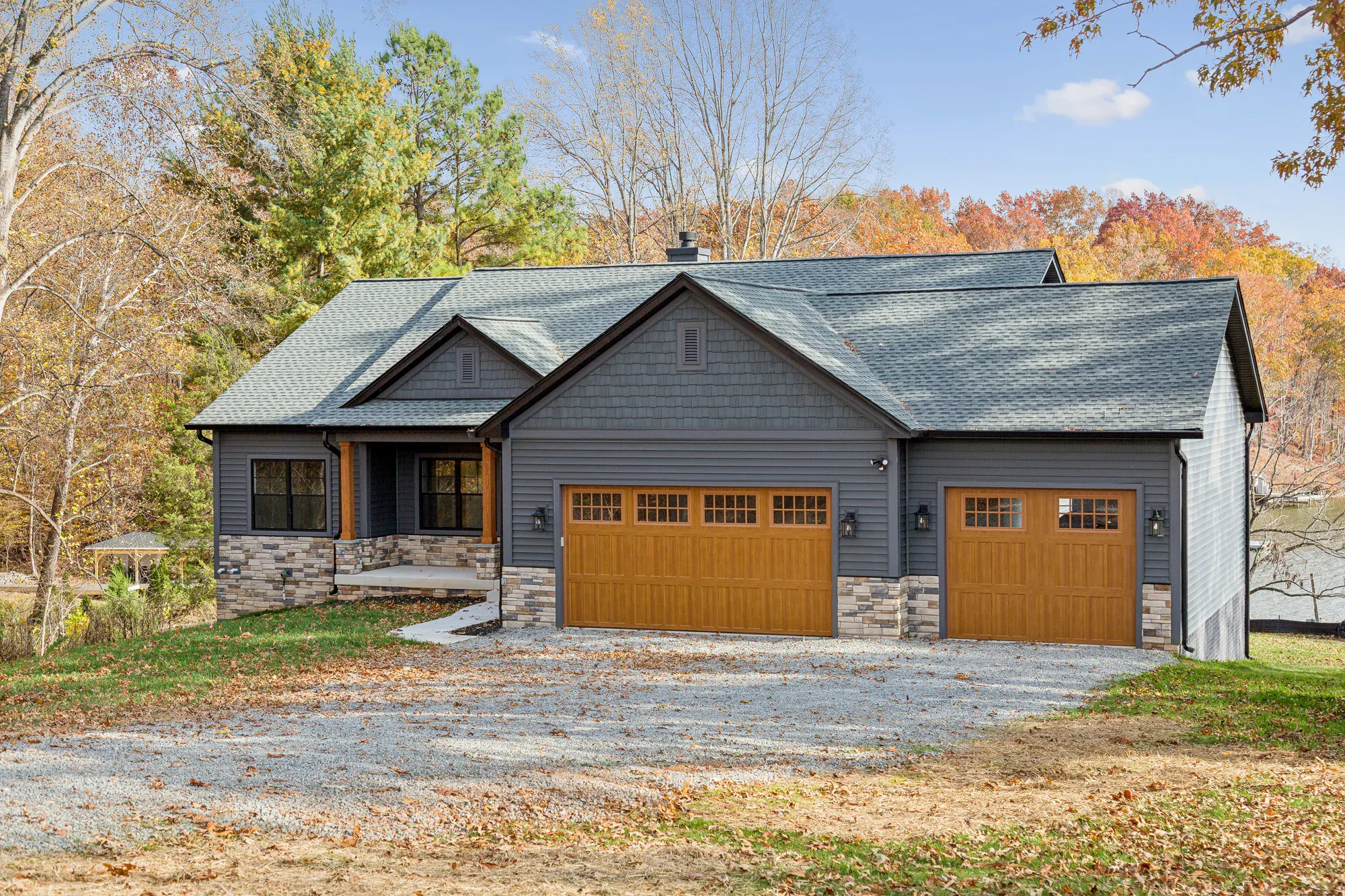 The full front elevation of a Spartan Homes custom craftsman home with gabled roofs, stone accents and autumn landscaping near Lake Anna, Virginia