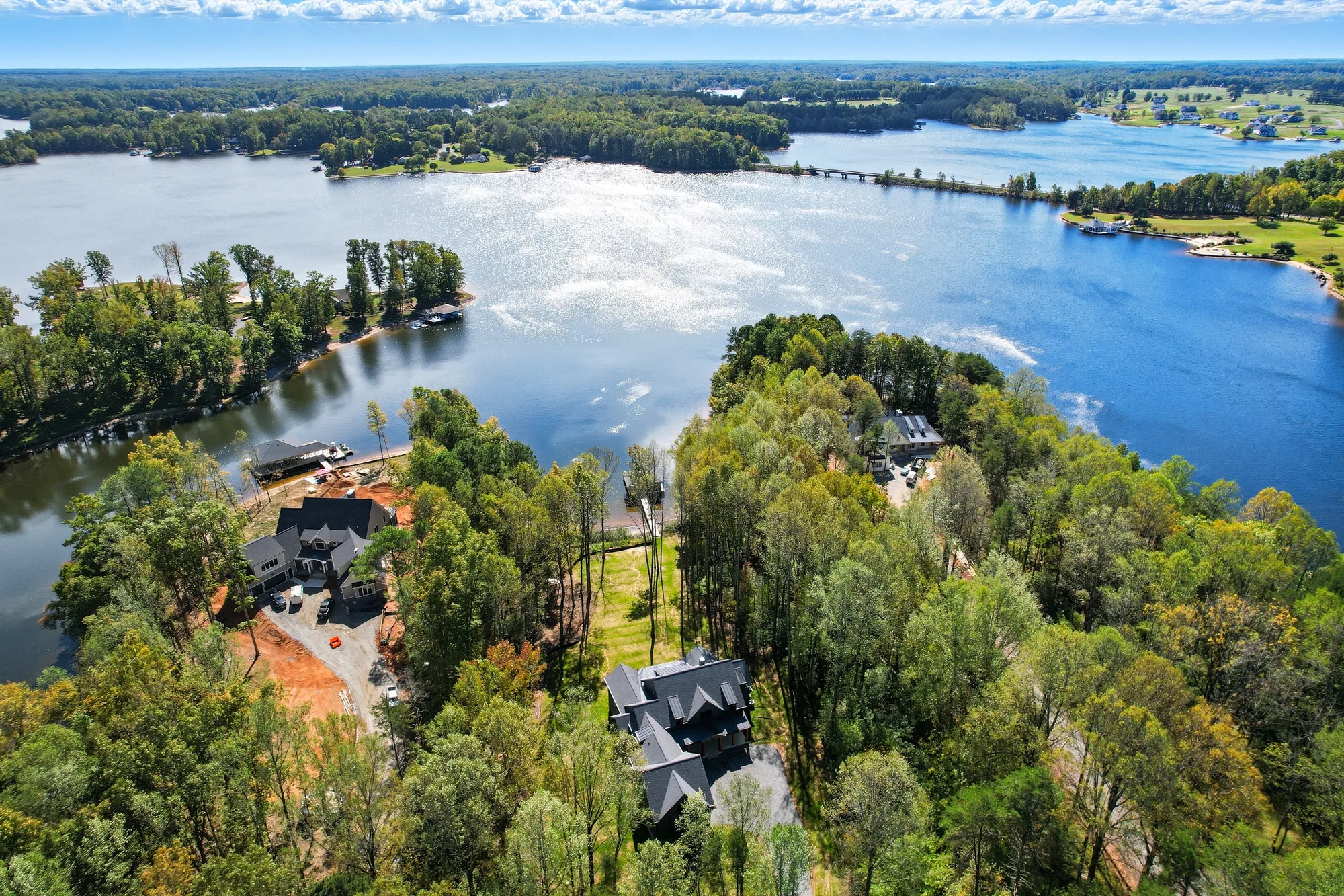 Wide aerial of Lake Anna, Virginia showing wooded shoreline homes and expansive open water near a Spartan Homes lakefront custom home.