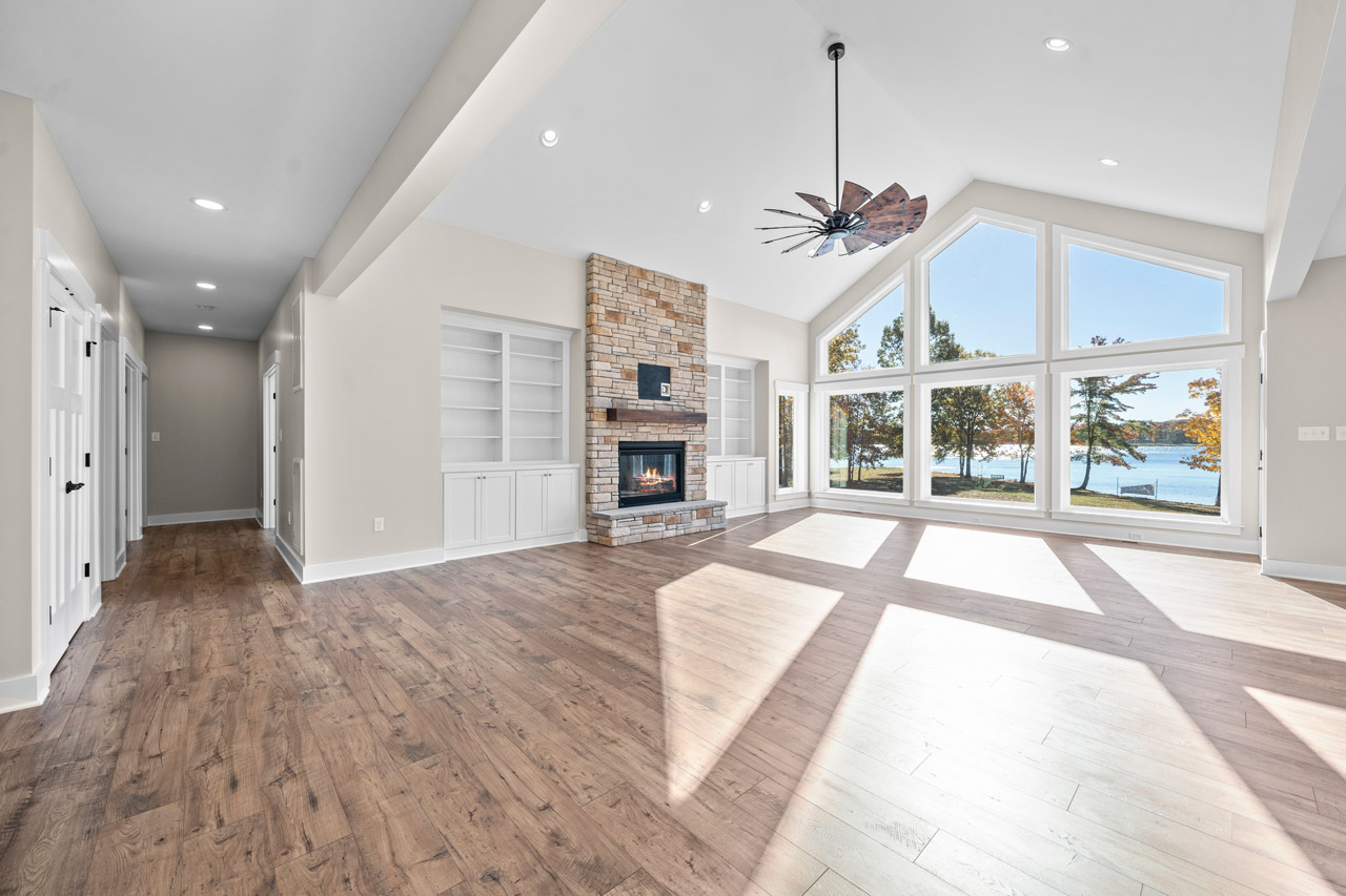 Open great room with a fireplace and a wall of windows looking over Lake Anna.