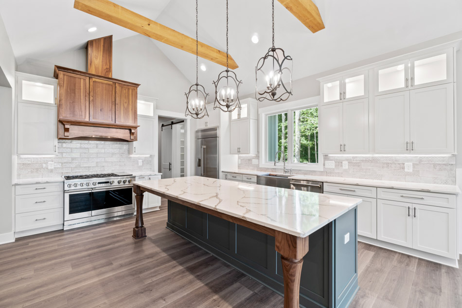 A custom kitchen with a walnut range hood, marble-topped island and a vaulted beamed ceiling