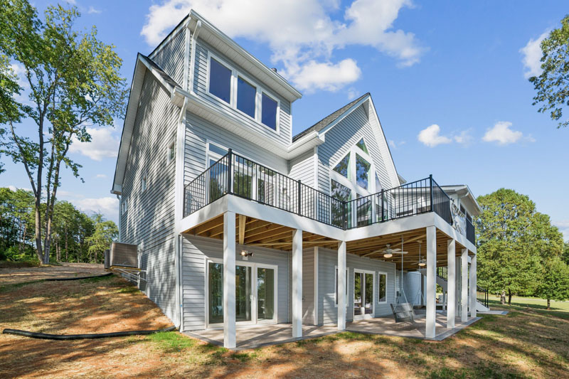 A custom home with a glass-walled rear elevation overlooking a quiet cove at Lake Anna