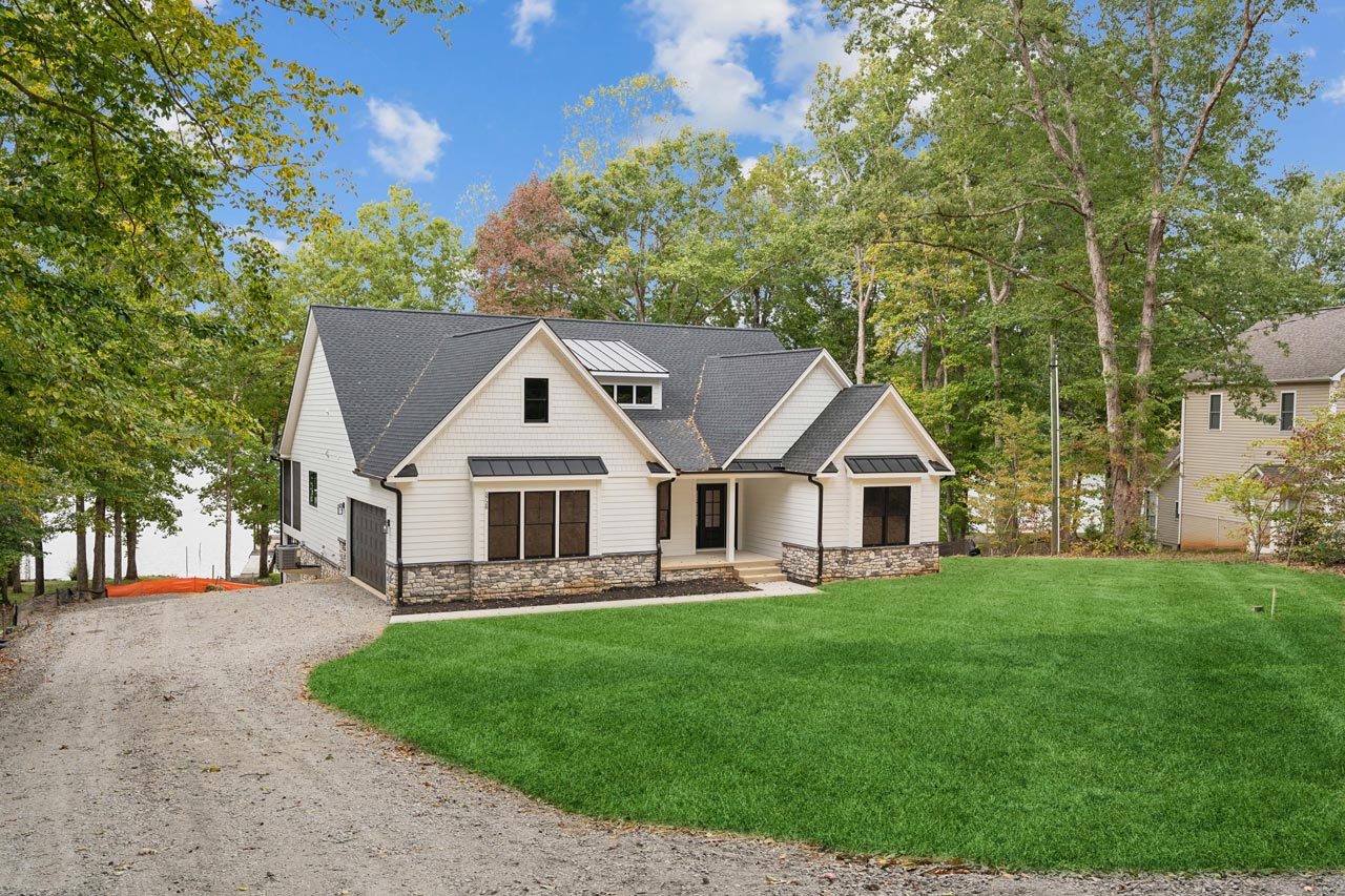 A white farmhouse custom home on the shoreline at Lake Anna, seen from the water